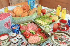 A breakfast table with various food items, including bread, cheese, meats, and fruits. - Ötztal Chalet (Sautens)
