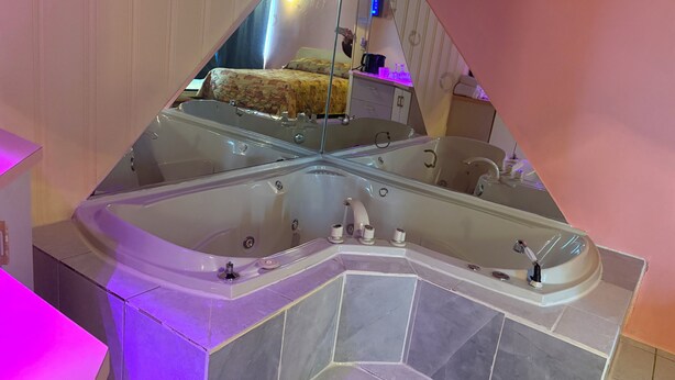 Un baño moderno con una bañera grande, un espejo y un tocador con lavabo.