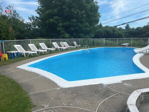 Una piscina con sillas reclinables blancas y una bandera.