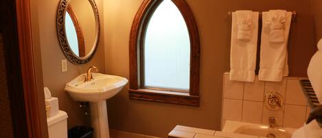 A bathroom with a white sink, a toilet, a vanity with a mirror, and a window.