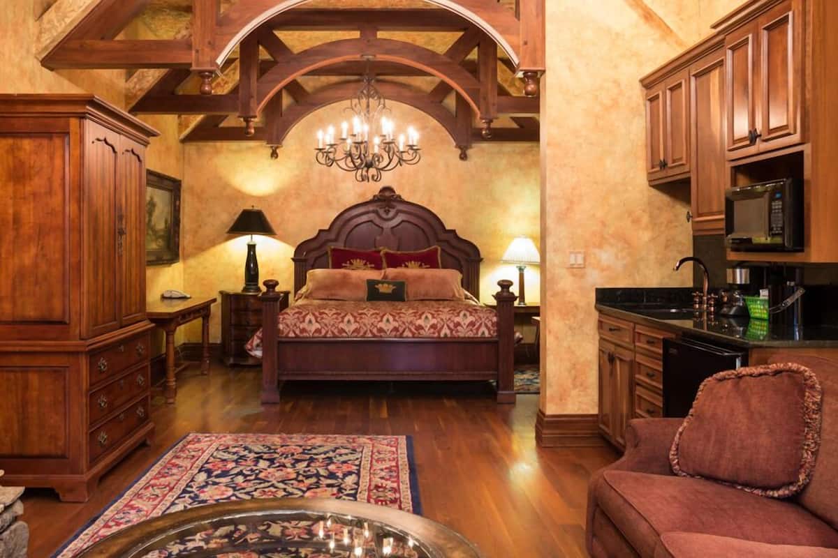 A traditional bedroom with a large bed, wooden furniture, and a chandelier.