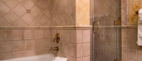 Un baño con bañera, cabina de ducha de cristal y paredes con azulejos color beige.