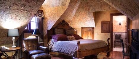 A bedroom with a wooden bed, leather armchair, and a small table with a lamp.