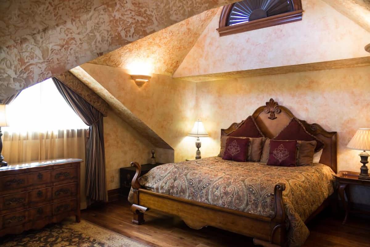 A bedroom with a large bed, wooden headboard, and two bedside lamps.