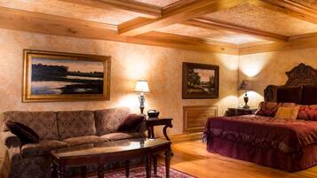 Une pièce confortable avec un canapé, un lit et une table. Des tableaux ornent les murs et une lampe est posée sur la table.