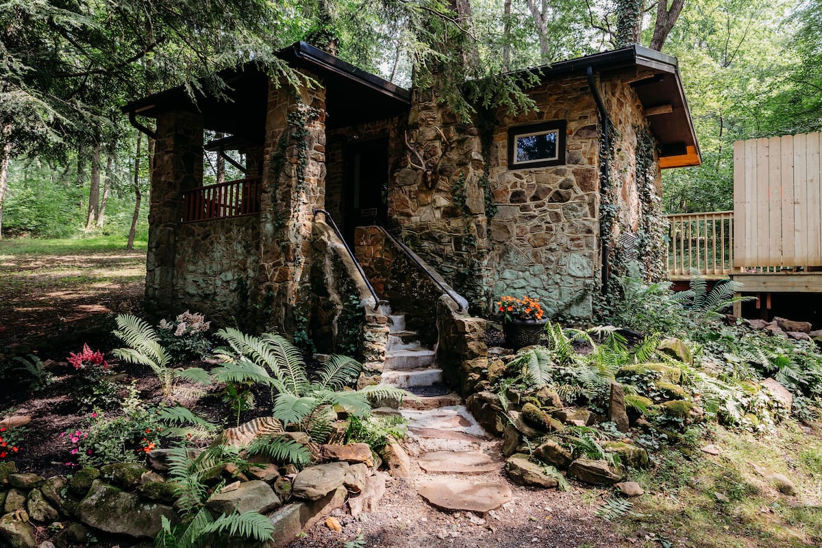 A stone cabin with a wooden deck and a staircase leading to a door.