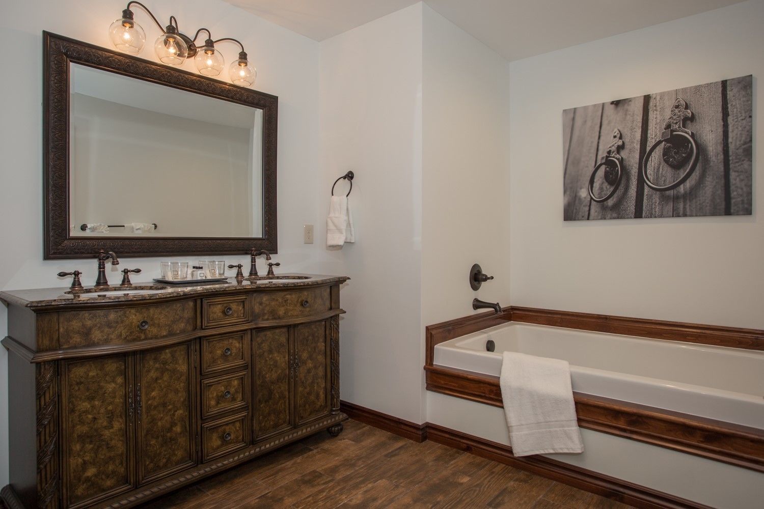 Une salle de bain avec un meuble-lavabo d’époque, un grand miroir, une baignoire et un porte-serviettes fixé au mur.