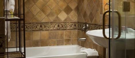 A bathroom with a freestanding bathtub, a glass shower enclosure, and a metal shelf unit.