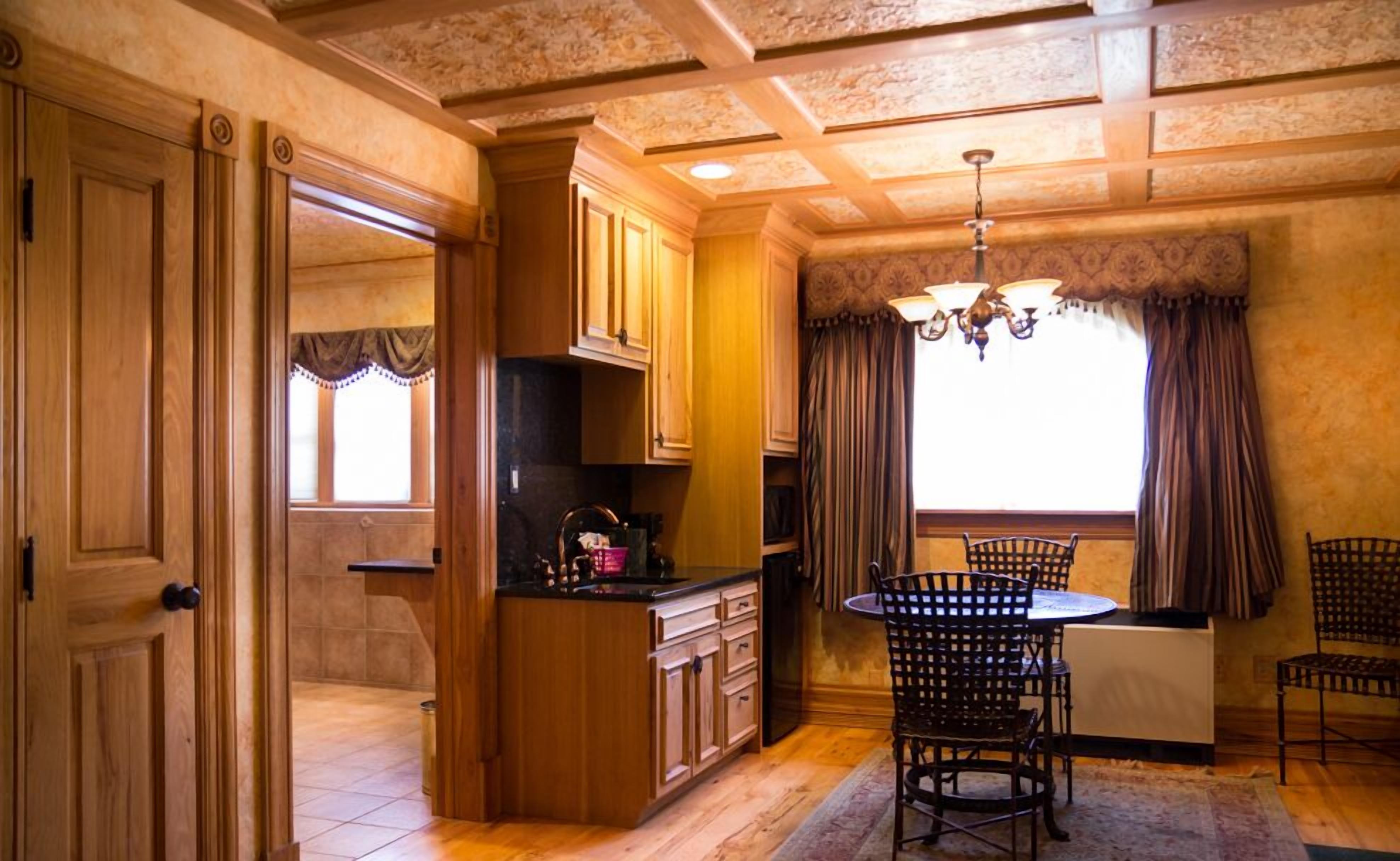 A kitchen with wooden cabinets, a dining table with chairs, and a chandelier.