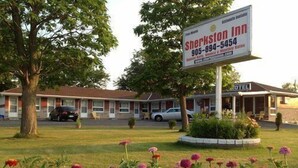 A motel with a signboard, a lawn, and a flower bed. - Sherkston Inn (Port Colborne)