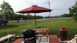 An outdoor patio with a grill, picnic table, and chairs. - Sherkston Inn (Port Colborne)