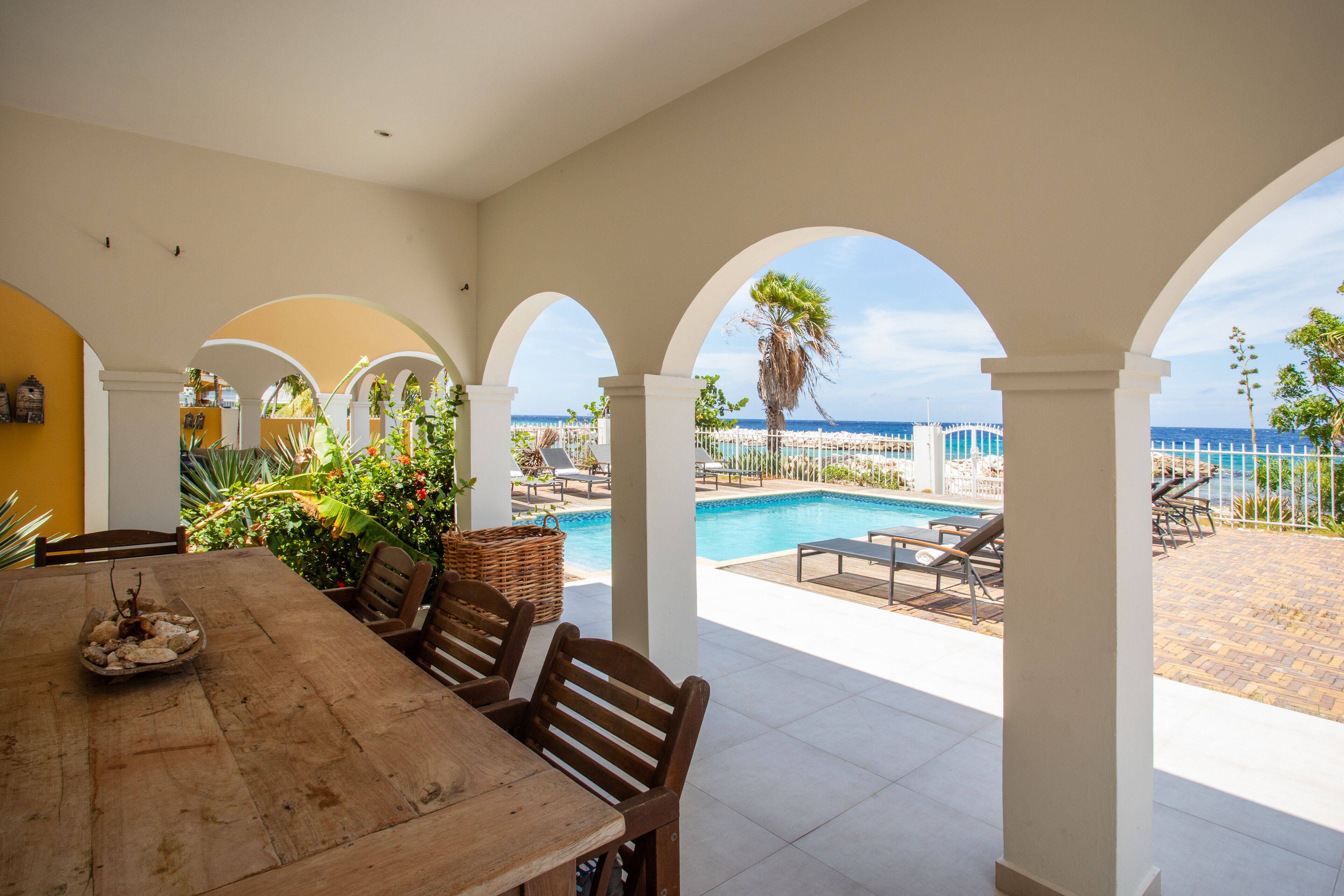 A dining area with a view of a pool and beach.