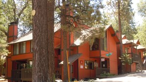 A row of orange cabins with a fire hydrant and white flowers in the front yard. - Escape For All Seasons (Big Bear Lake)