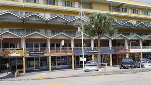 A multi-story building with various shops on the ground floor, including a bakery and a lottery center. - Royal Palm Suite Hotel (Port of Spain)