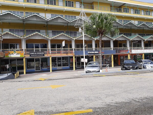 A multi-story building with various shops on the ground floor, including a bakery and a lottery center. - Royal Palm Suite Hotel (Port of Spain)