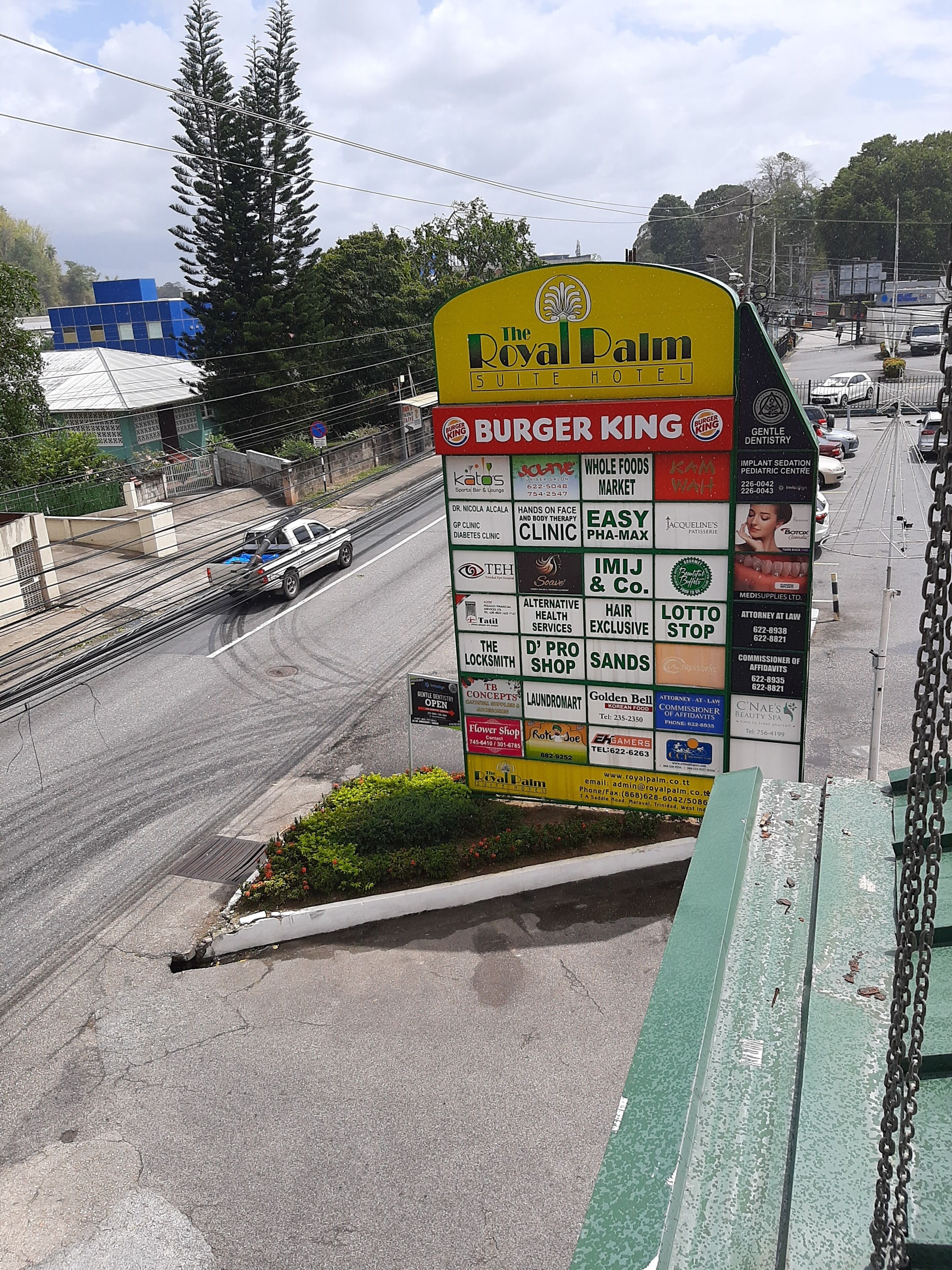 A large signboard with multiple business advertisements, including a Burger King, a dental clinic, and a lottery stop.