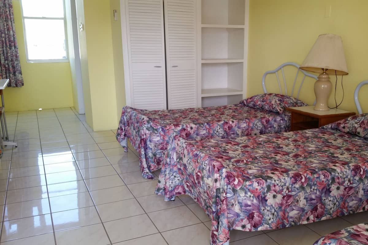 Ein Schlafzimmer mit zwei Betten, einem Nachttisch, einer Lampe und einem Kleiderschrank.