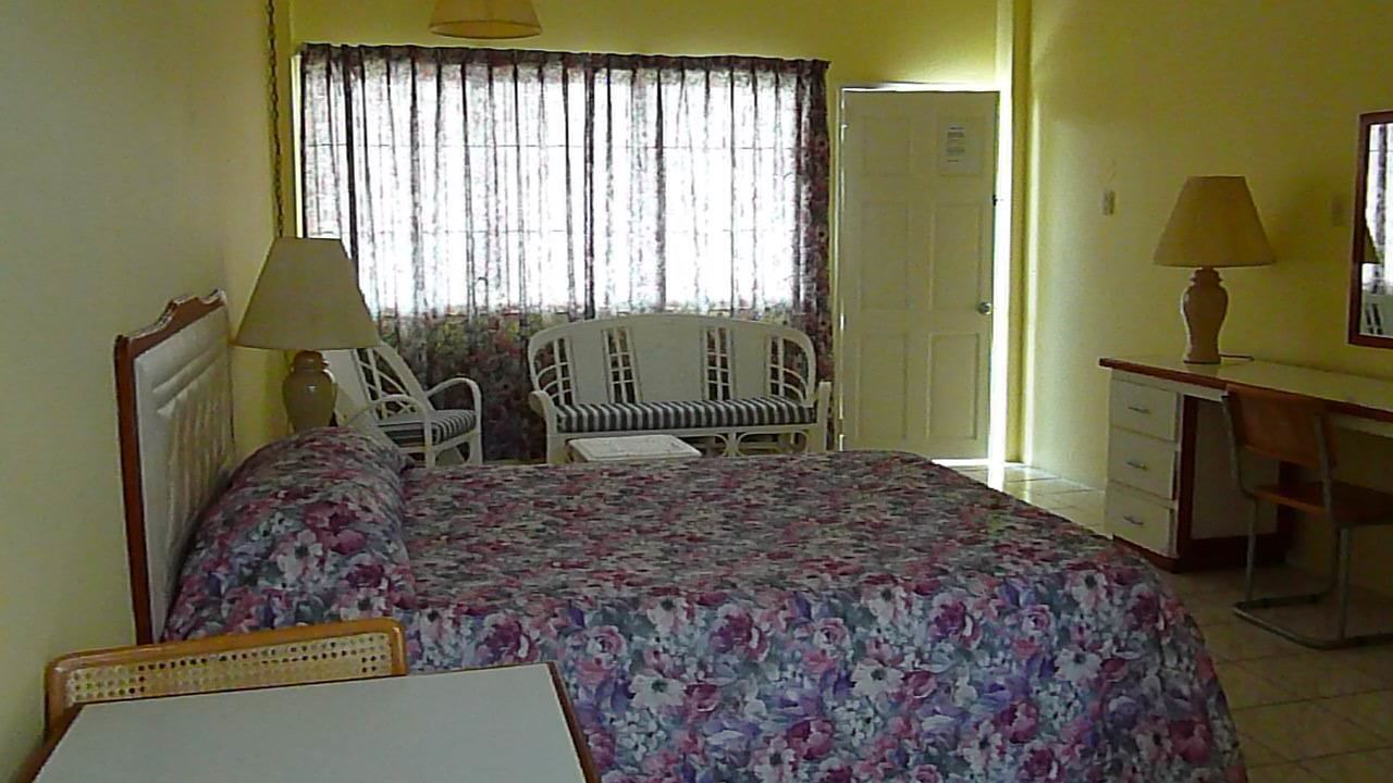A bedroom with a bed, a chair, a desk, and a lamp.