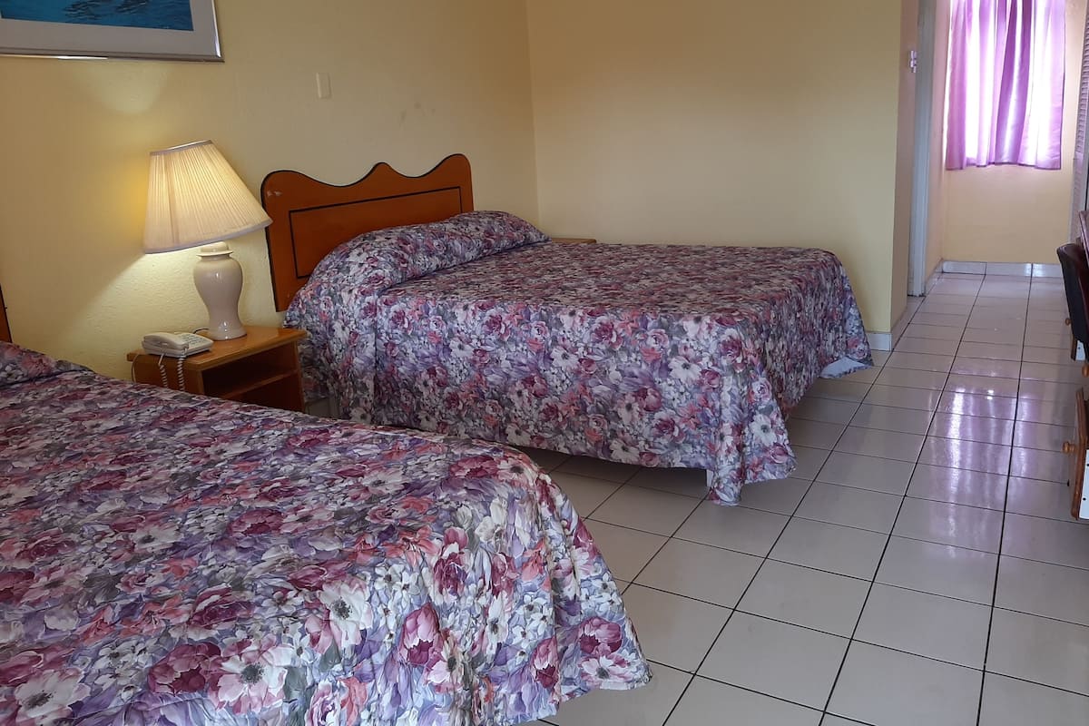 Ein Hotelzimmer mit zwei Betten, einem Nachttisch mit Lampe und einem Bild an der Wand.