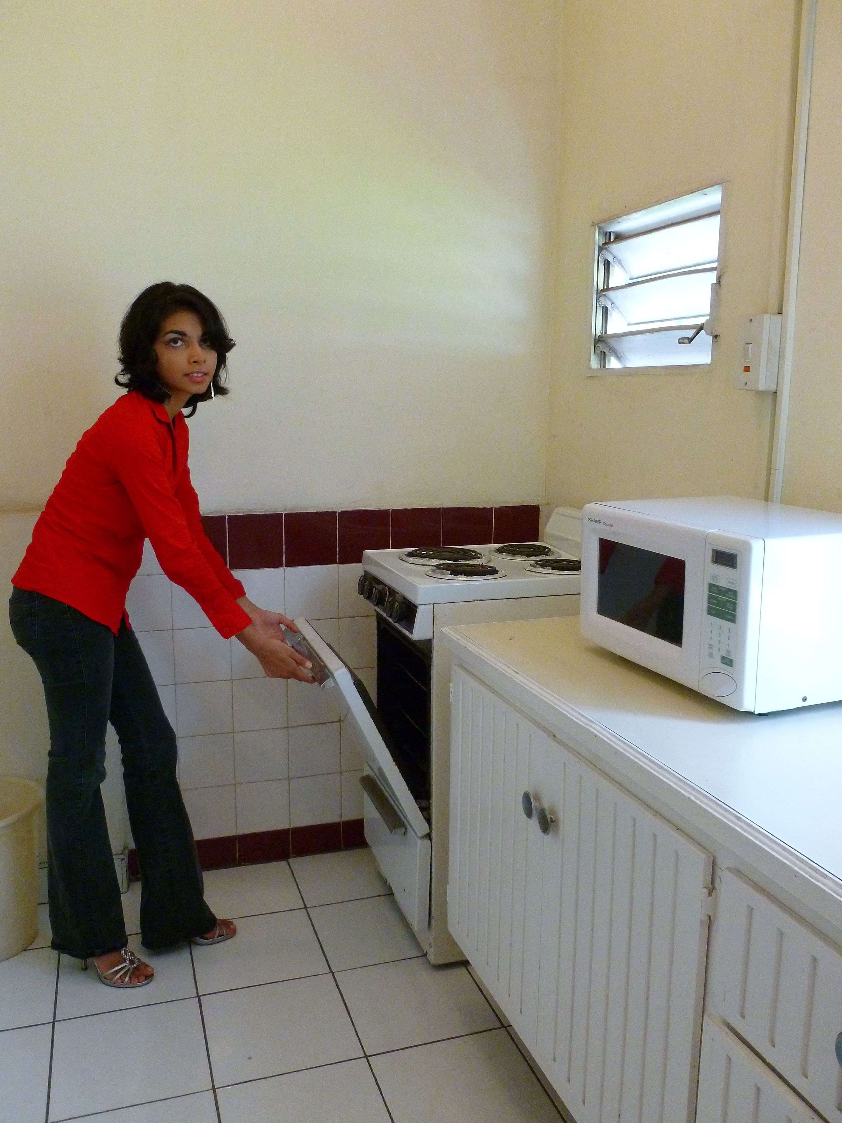 A kitchen with a stove, oven, microwave, and a window above the stove.