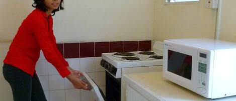 A kitchen with a stove, oven, microwave, and a window above the stove.