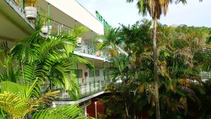 A multi-story building with balconies, surrounded by lush tropical vegetation. - Royal Palm Suite Hotel (Port of Spain)
