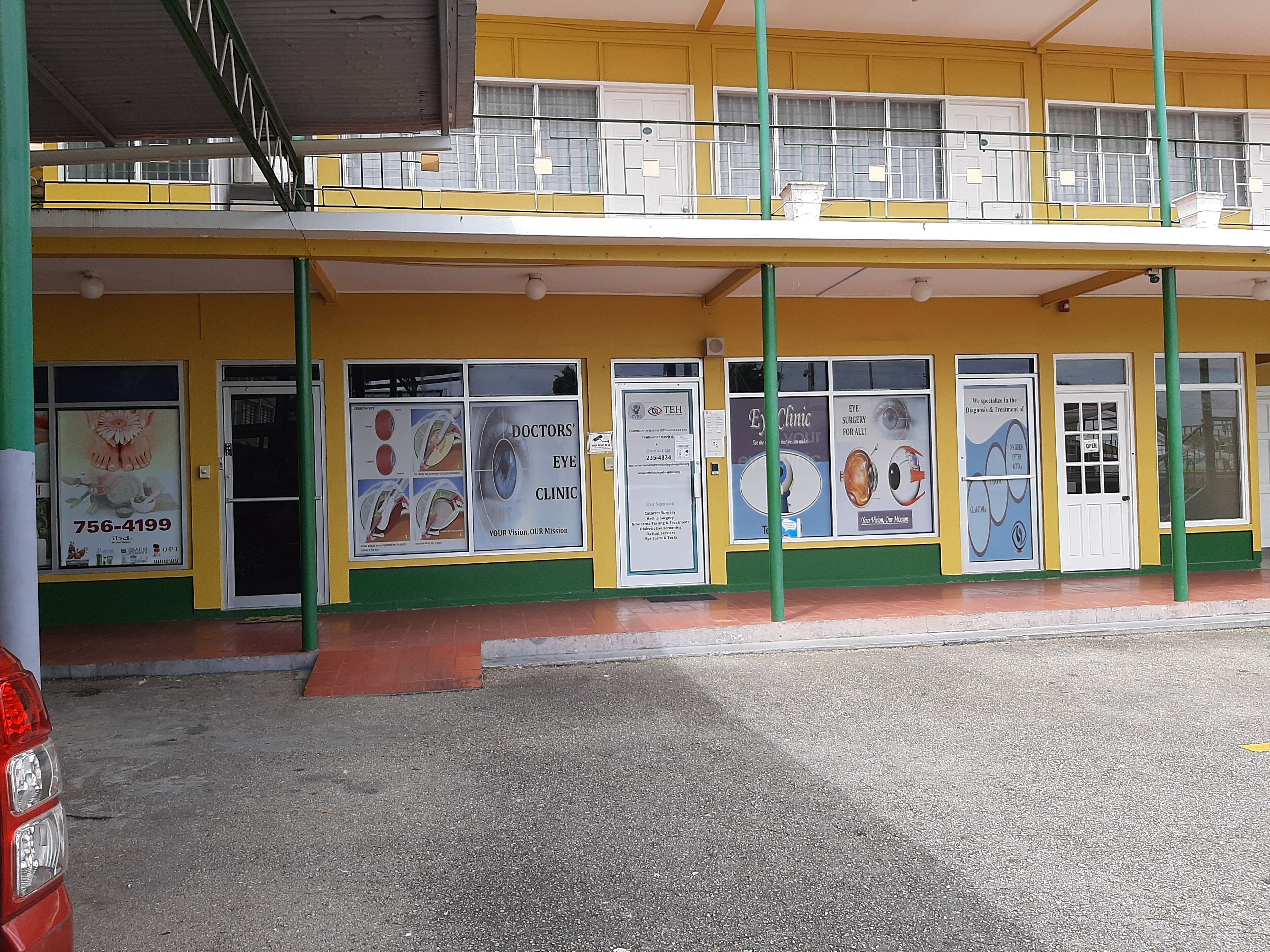 A building with multiple storefronts, including an eye clinic with visible signage and a contact number.