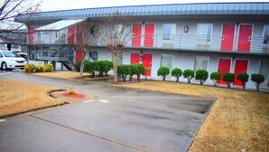 Un motel à deux étages avec des portes rouges et une allée couverte.