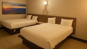 Une chambre d’hôtel avec deux lits, une table de chevet et un tableau représentant un coucher de soleil accroché au mur.