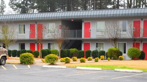 Un motel avec un parking, un VUS beige et un camion rouge.