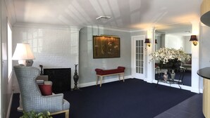 A reception area with a reception desk, a seating area with a chair and a bench, a fireplace, and a wall-mounted sign reading "The Atlantic Inn". - Atlantic Inn (Wethersfield)