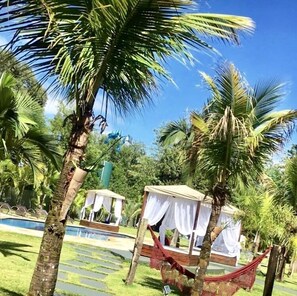 A pool area with palm trees, a hammock, and a covered seating area. - La Dolce Villa (Avare)