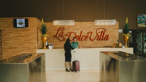 A reception desk with a wooden panel wall and a large sign reading "La Dolce Vita". - La Dolce Villa (Avare)