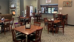 A restaurant with multiple wooden tables and chairs, a stone fireplace, and a sign that reads "Christo's Pub".