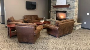 A cozy lounge area with leather sofas, a flat-screen TV, and a stone fireplace.