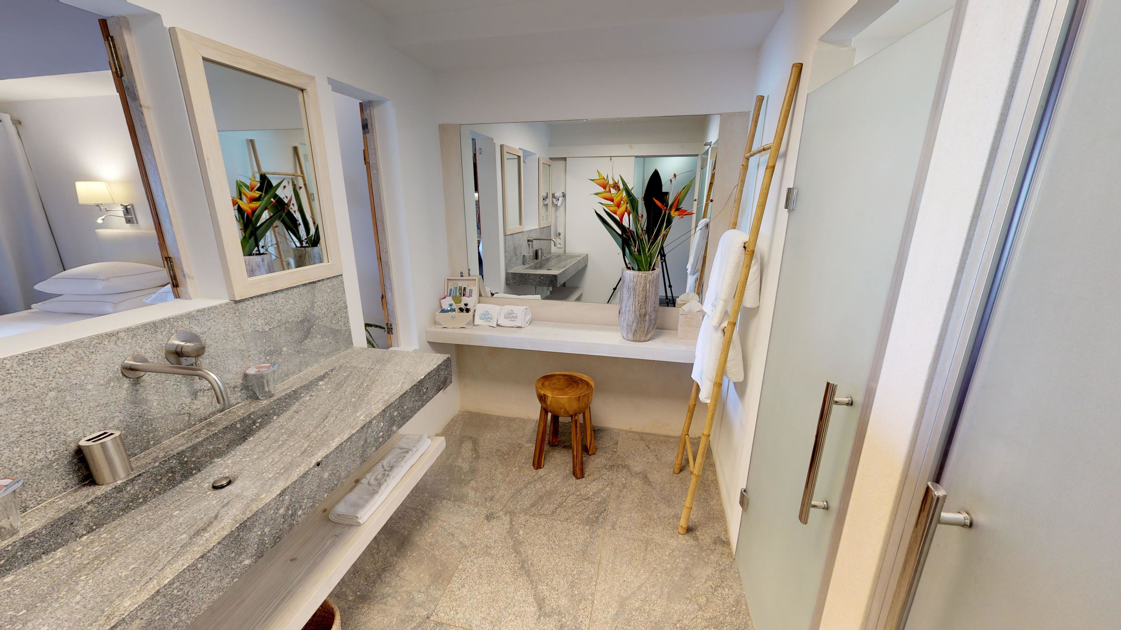 Une salle de bain moderne avec un comptoir en granit, un lavabo, un miroir, un meuble-lavabo, des toilettes et un tabouret en bois.
