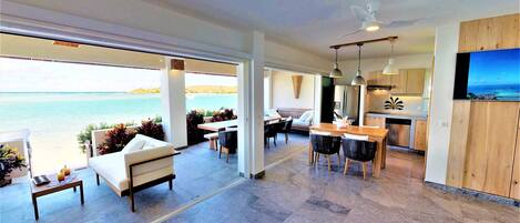 A spacious living area with a view of the sea, a dining area, and a kitchen with wooden cabinets.