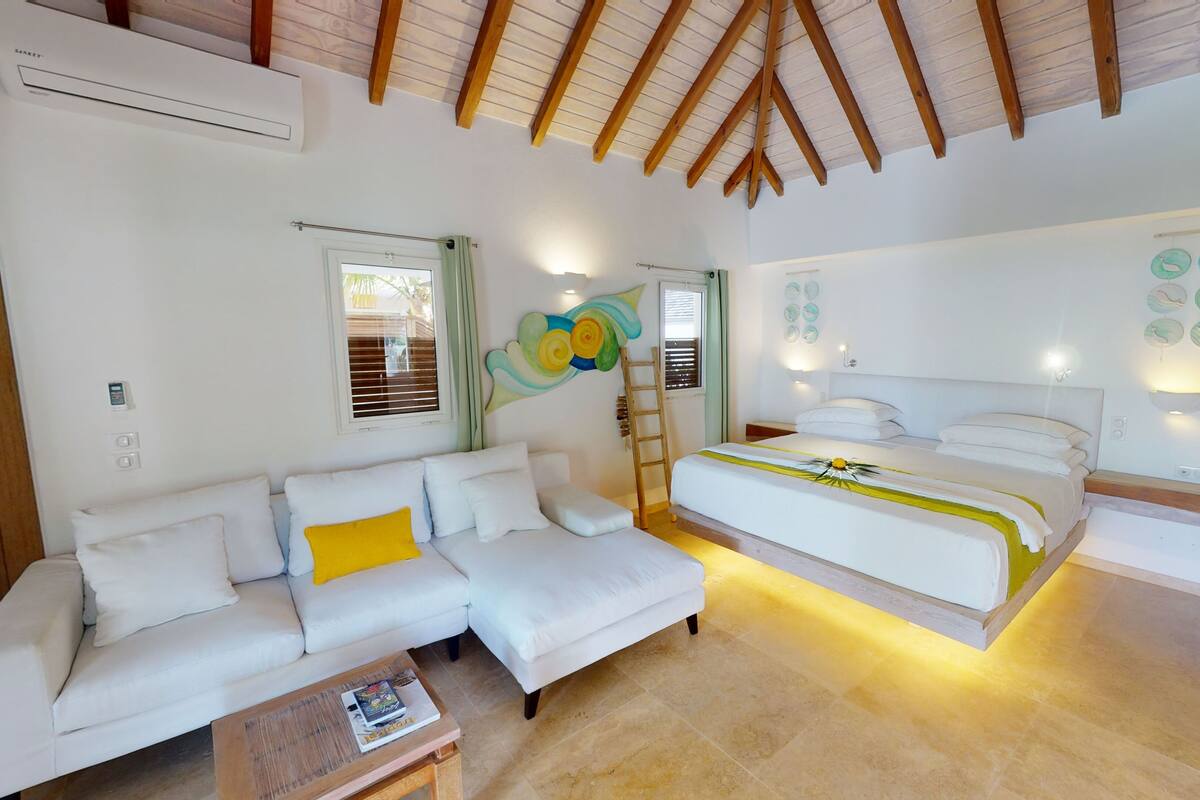 Ein Schlafzimmer mit Bett, Schlafsofa, Nachttisch und Fenster.