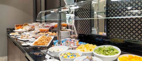 A buffet with various food items including fruits, cereals, and desserts.
