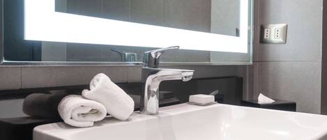Un baño moderno con un lavabo blanco, un espejo y una toalla en la encimera.