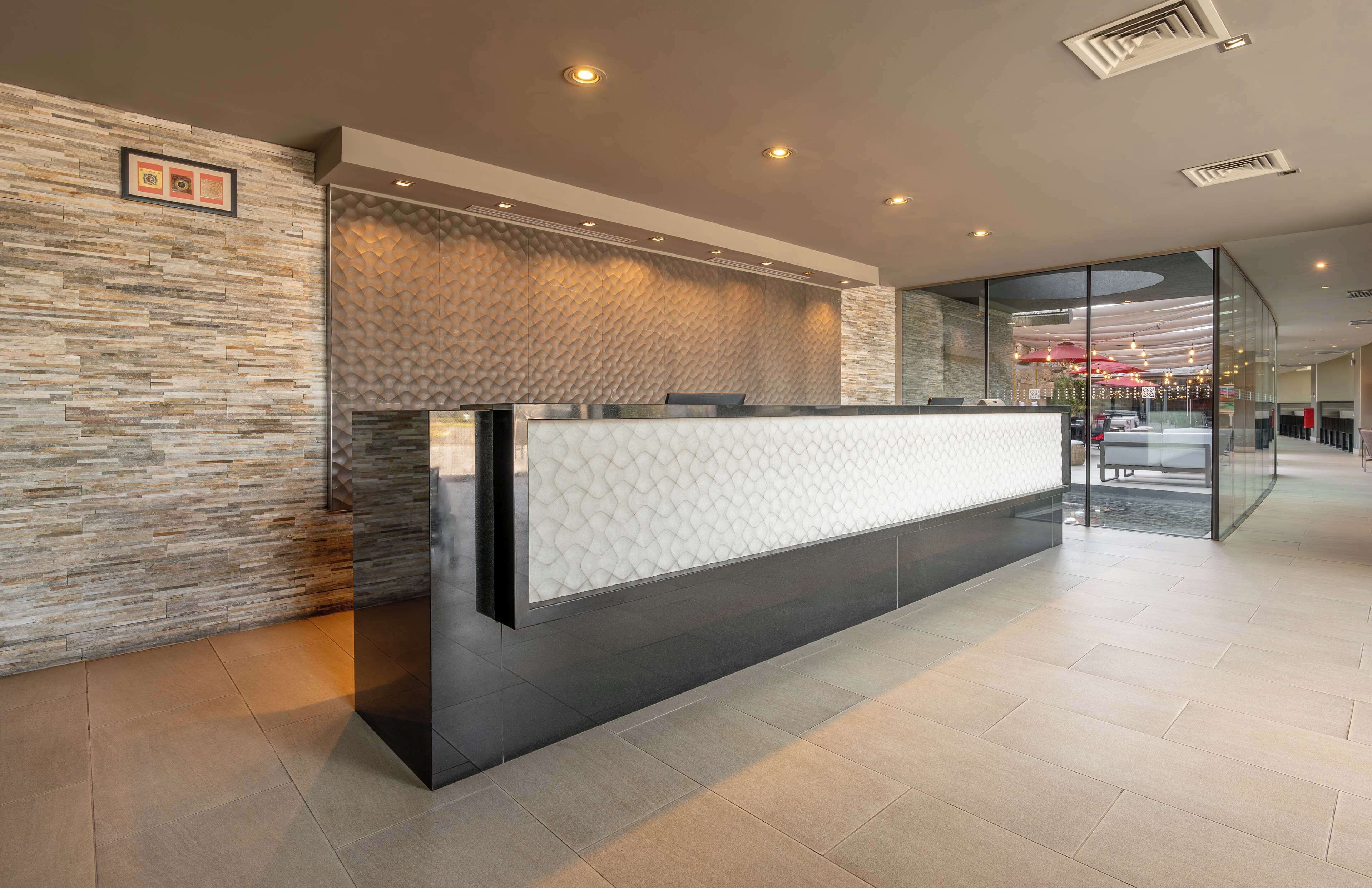 A reception desk with a textured stone wall, a glass partition, and recessed lighting.