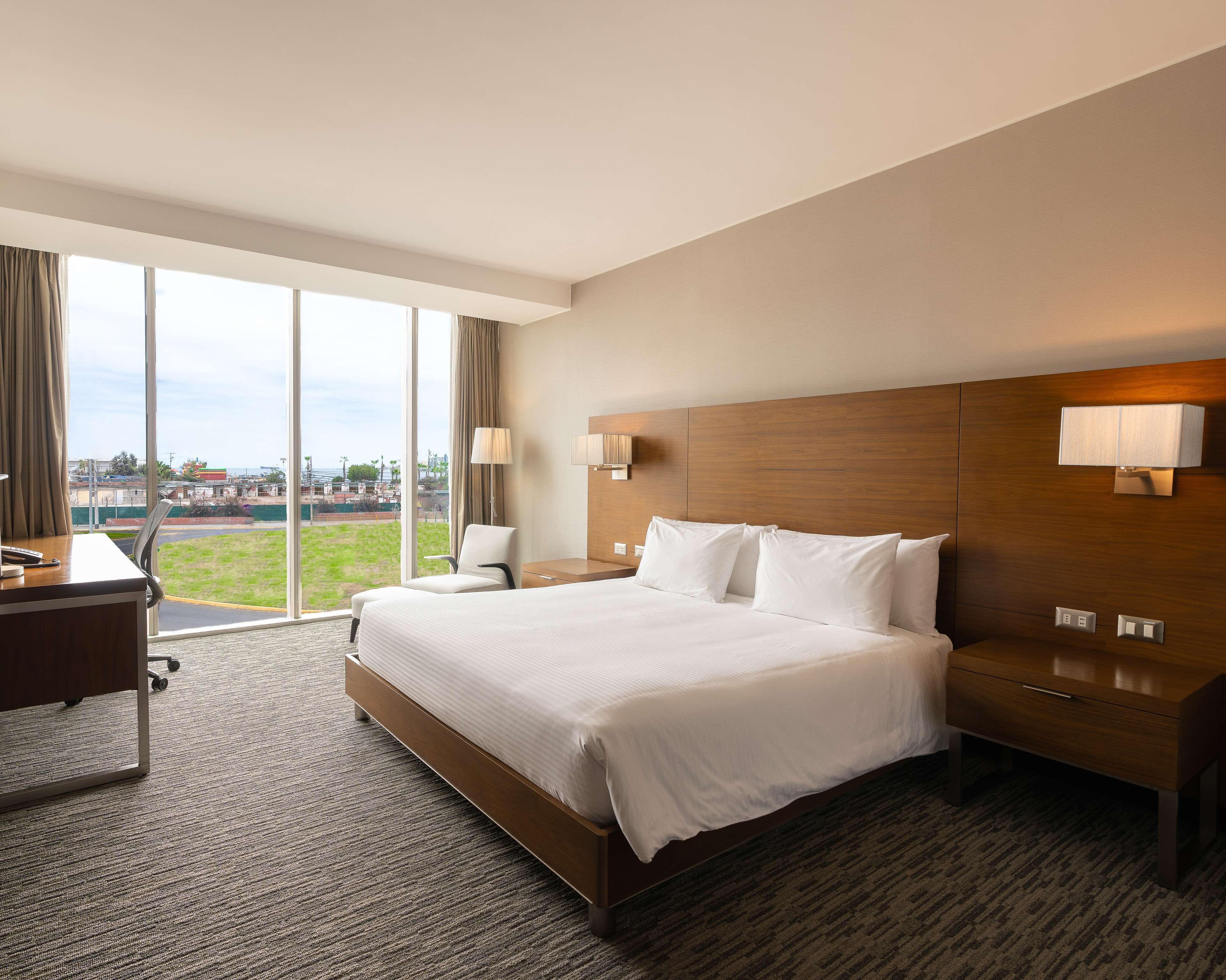 Een hotelkamer met een groot bed, een bureau en een stoel. Een raam biedt uitzicht op het omliggende landschap.