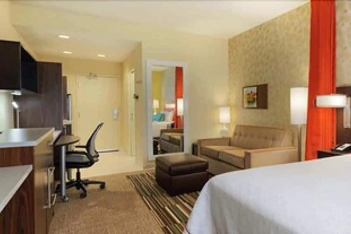 Une chambre d’hôtel équipée d’un lit, d’un bureau, d’une chaise, d’un canapé et d’une télévision.