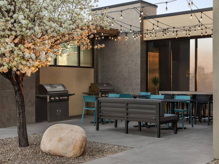 An outdoor patio with a barbecue grill, seating area, and string lights.