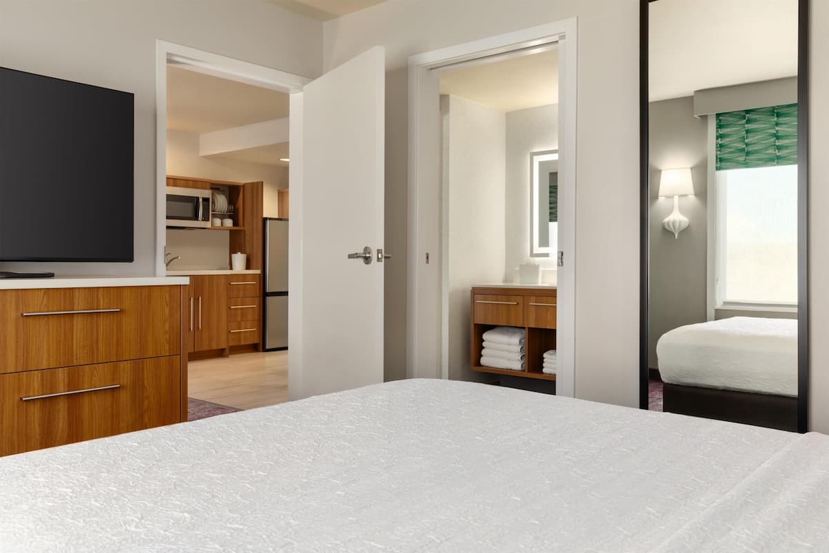 Une chambre d’hôtel comprenant un lit, une télévision, une salle de bain avec un miroir et un coin cuisine.