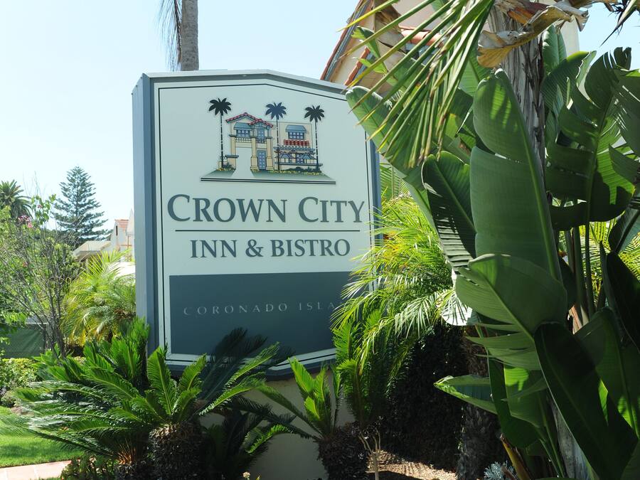 Cartell de Crown City Inn & Bistro amb un jardí tropical al primer pla.