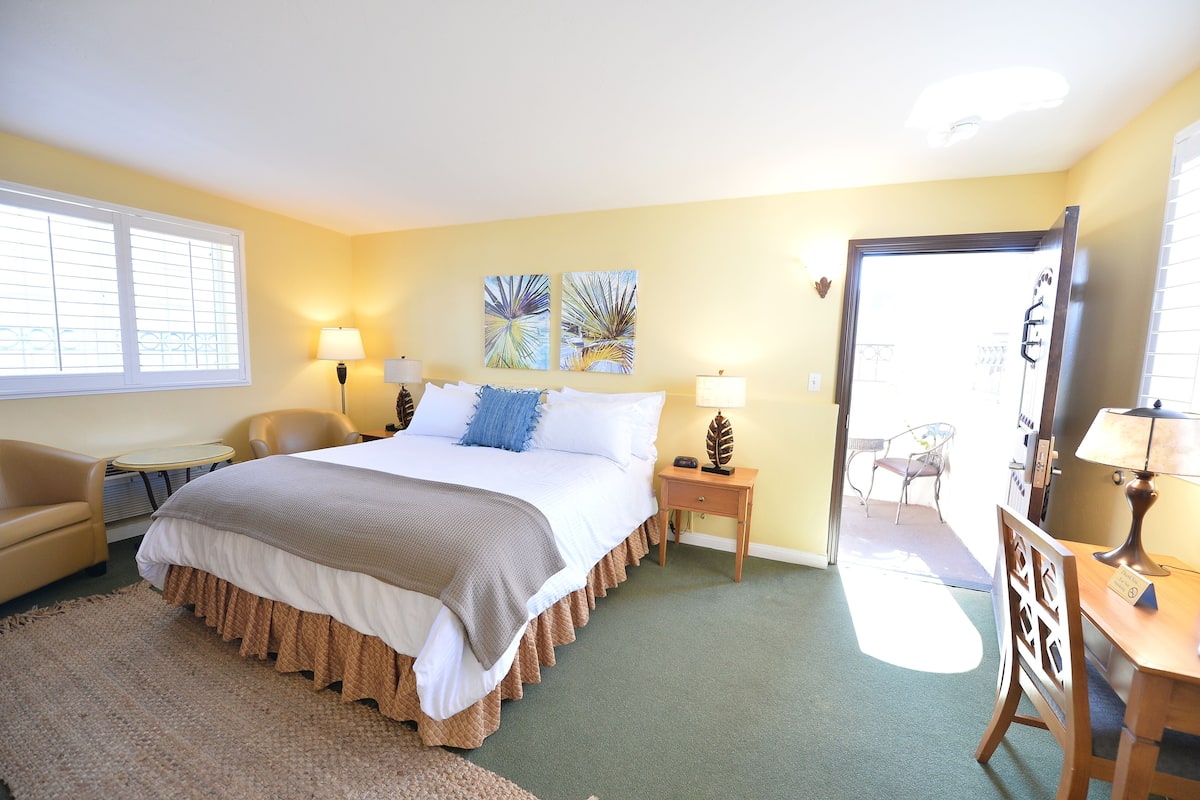 A bedroom with a bed, bedside tables, a chair, and artwork on the walls.