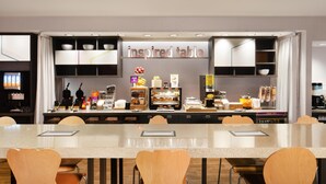 Un restaurant d’hôtel moderne doté d’une longue table conviviale, de différents buffets et d’un panneau indiquant « table inspirée ».