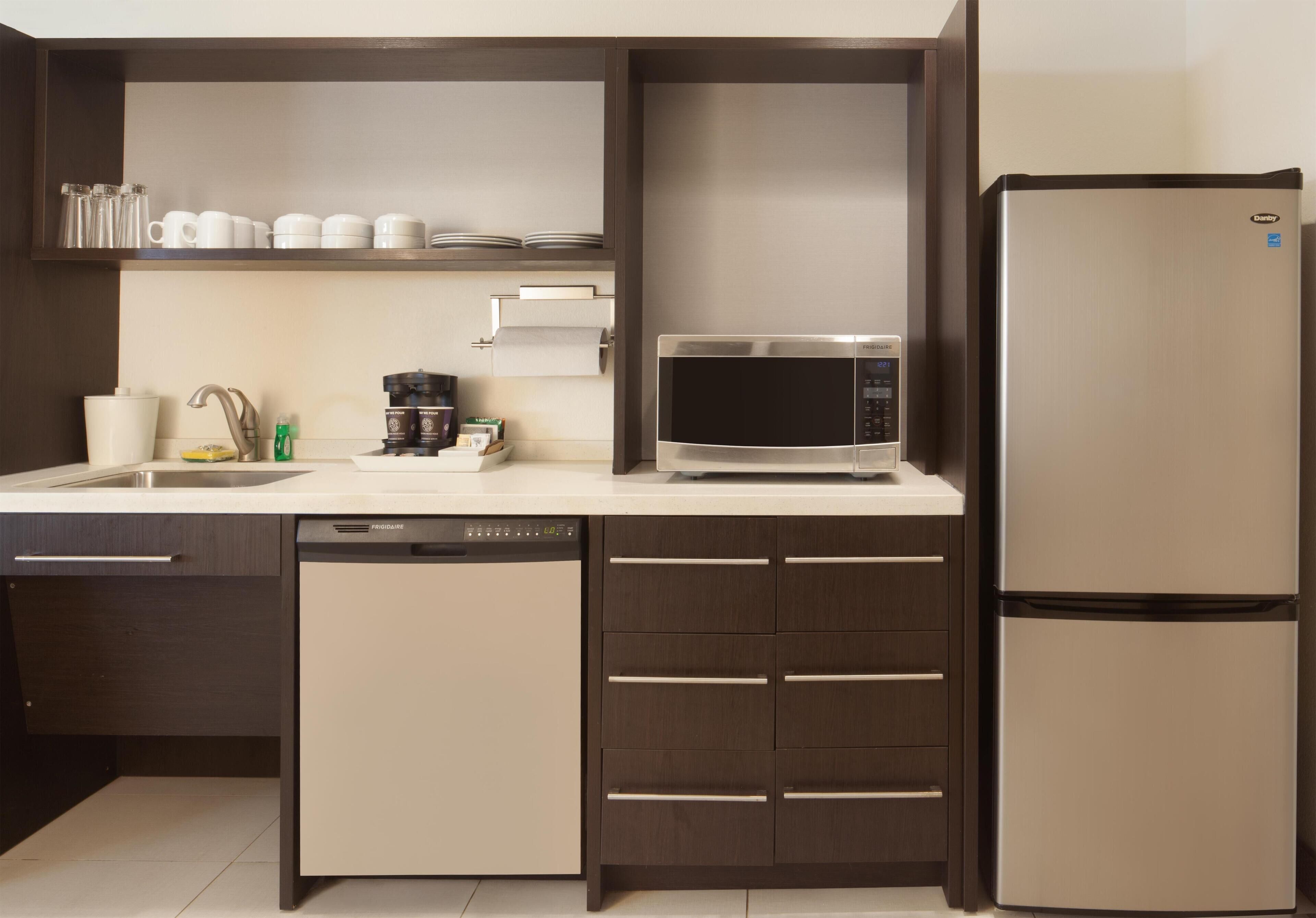 A modern kitchen with a dishwasher, microwave, and refrigerator.