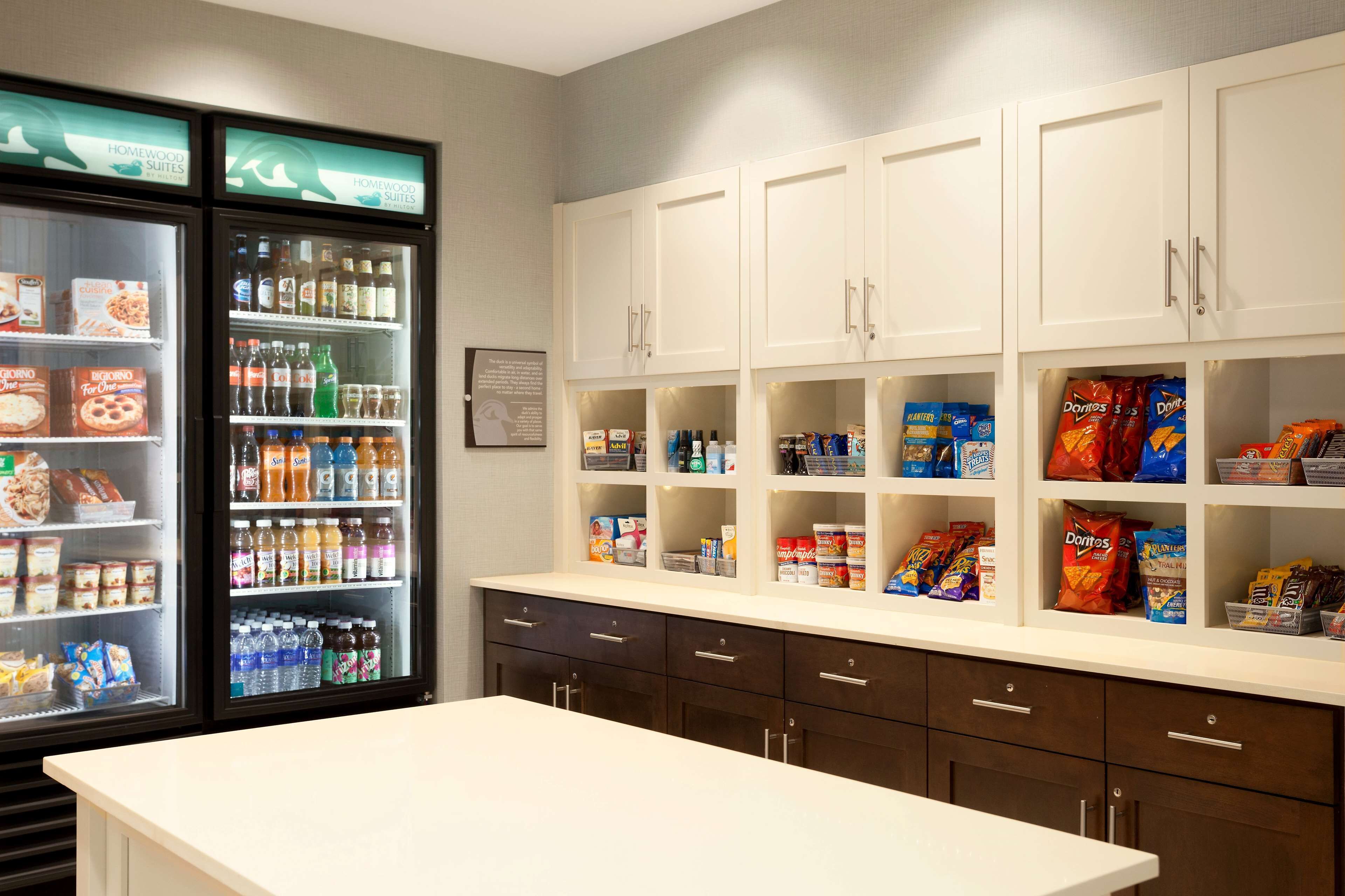 A hotel pantry with shelves stocked with snacks, beverages, and condiments.
